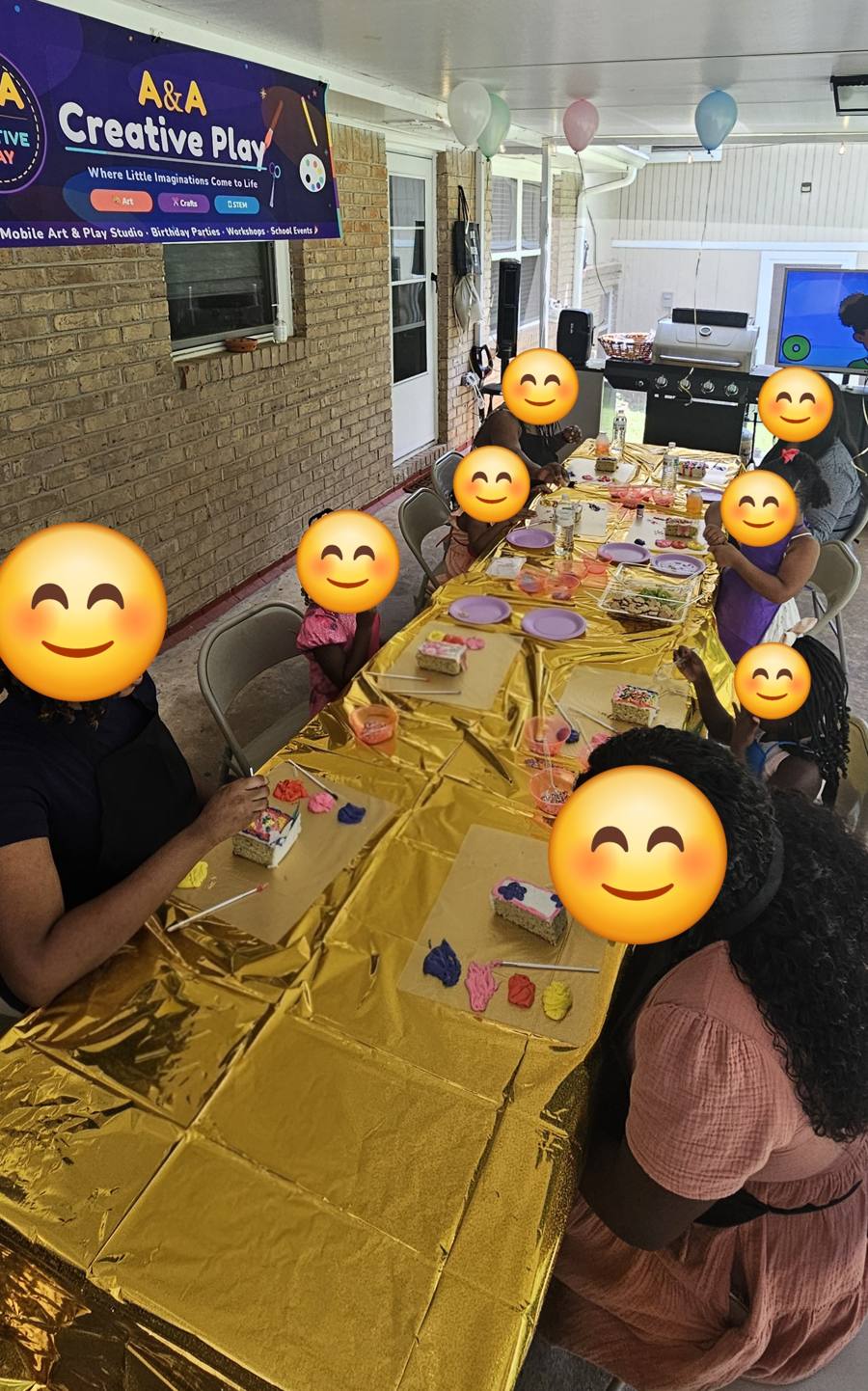 Group photo of kids and helpers at the cake decorating table with A&A Creative Play banner